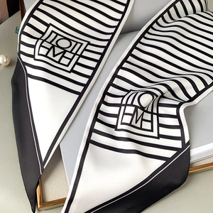 Close-up of silk neckerchief with black and white stripes and geometric logo detail