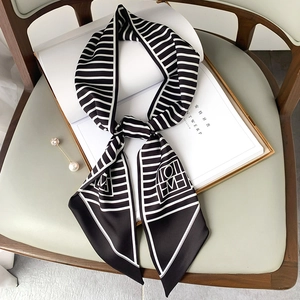 Elegant black and white striped silk scarf with geometric logo on stylish magazine