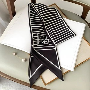 Detail of black and white striped skinny scarf with geometric logo on a stylish table