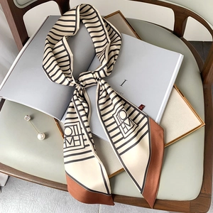 Detail of a striped silk scarf tied on a magazine with geometric letters and brown edges