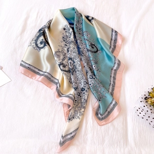 Elegant paisley patchwork square silk scarf in beige and blue on a white textured background