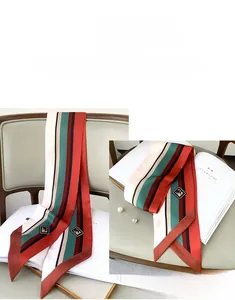 Close-up of striped silk twilly scarf with diamond emblem tied on a leather chair