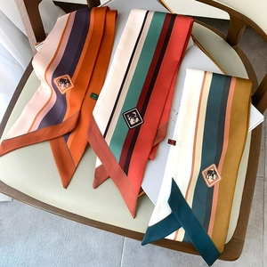 Detailed macro view of three striped silk twilly scarves with elephant logos on a chair
