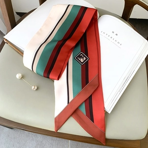 Detailed view of striped narrow scarf with equestrian leather tag in warm tones