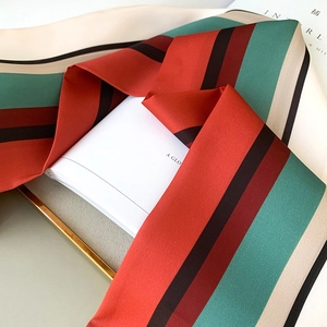 Macro view of multi-color striped silk scarf with orange and blue satin texture