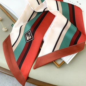 Detail of vintage striped silk scarf with horse logo on a gold tray with magazine