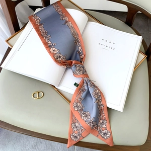 Détail d'un foulard étroit en soie à fleurs sur magazine avec une texture soyeuse et douce