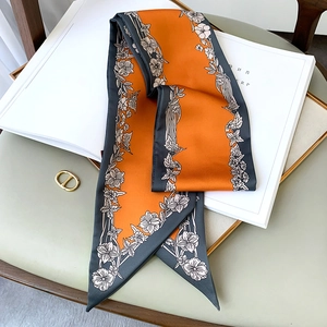 Détail d'un foulard étroit à fleurs en soie brillante de couleur orange et gris foncé
