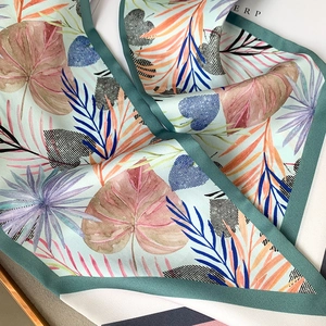 Détail macro du foulard en satin à imprimé tropical avec texture lisse et bordure verte