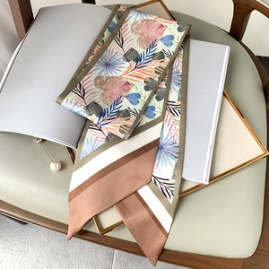 Détail d'un foulard en soie twilly à imprimé tropical avec une broche en perles