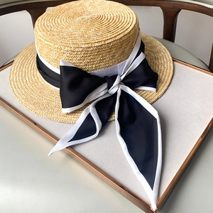 Elegante sombrero de paja de rafia de copa plana con un lazo de cinta de seda negra