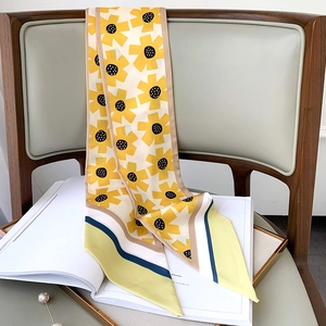 Detail of yellow sunflower silk scarf draped on chair with artistic background