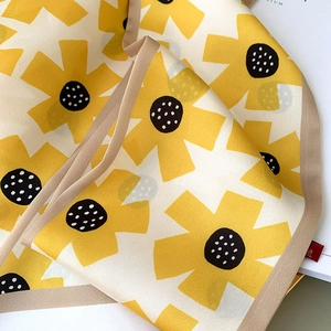 Detailed macro shot of yellow floral pattern and brown stitched edge on skinny scarf