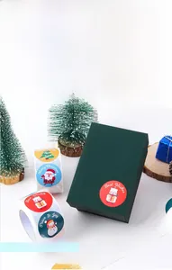 Close-up of colorful cartoon snowman and Santa stickers on a green Christmas gift box