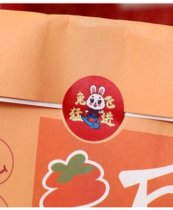 Close-up of a festive red rabbit sticker on a kraft paper gift bag with persimmon motifs