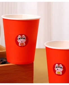 Close-up of red paper cup with cartoon rabbit sticker and lucky character for New Year