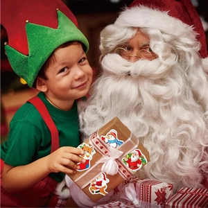 Child holding gift box decorated with holographic Santa and snowman Christmas stickers