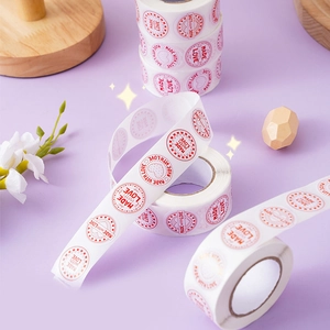 Round 'Made with Love' stickers on a roll with red heart accents for gift packaging