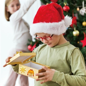 Close-up of holographic Christmas stickers on a gift box next to a plush Santa hat