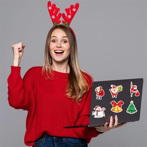 Cheerful woman holding a laptop decorated with holographic Christmas stickers and festive icons