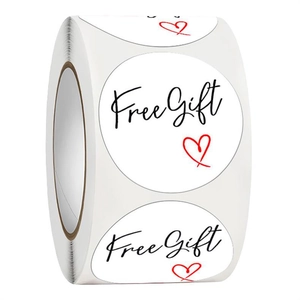 Close-up of a roll of round white Free Gift stickers with black text and red heart