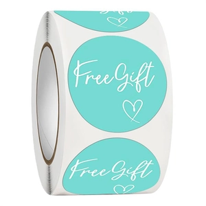 Macro shot of teal Free Gift stickers roll with white heart for product packaging