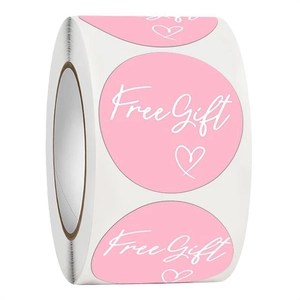 Macro detail of round pink Free Gift stickers roll with white heart for gift packaging