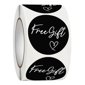 Close-up of black round sticker with white Free Gift text and heart for gift packaging