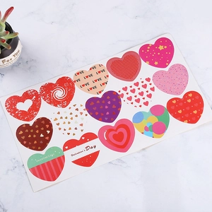 Sheet of heart-shaped Valentine's Day stickers with gold foil accents on marble surface