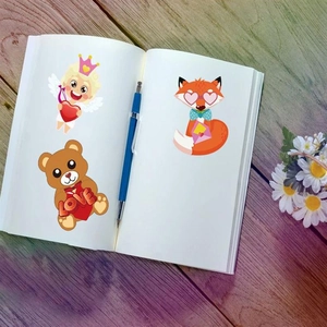 Close-up of Valentine's Day heart stickers with Cupid and bear on a notebook