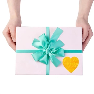 Detail of glitter heart sticker on pink gift box with mint green ribbon and bow