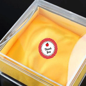 Detail von Thank You Aufkleber mit Apfel-Design auf einer klaren Geschenkbox mit gelber Einlage