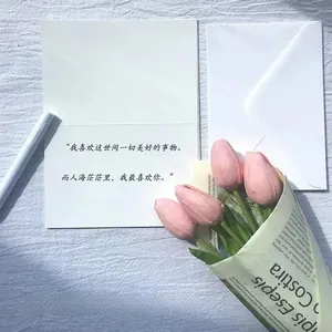 Close-up of minimalist white folding card with envelope and pink tulip floral decoration