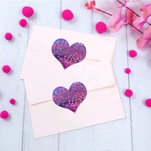 Holographic purple heart laser stickers on pink envelopes with a warm decorative background