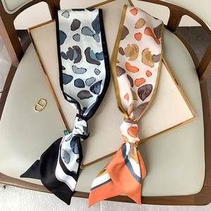 Detailed view of elegant narrow silk scarves in stone patterns on a decorative tray
