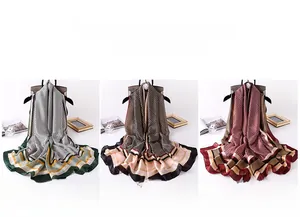 Detail of silk-feel scarves in green, beige and red with elegant geometric letter patterns