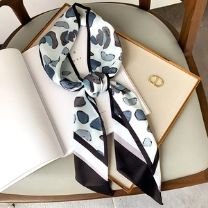 Chic skinny silk scarf with abstract pebble pattern and color-block stripes on wood chair
