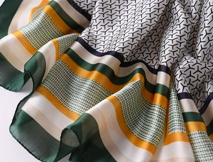 Detailed macro view showing the glossy satin texture and geometric pattern of the silk scarf