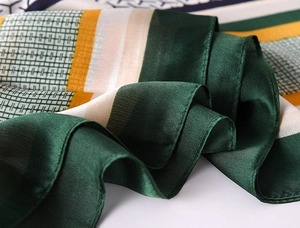 Detailed close-up of dark green and yellow silk scarf with geometric stripe patterns