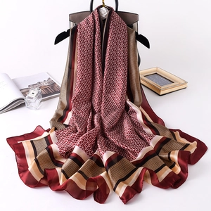 Burgundy silk scarf with geometric T pattern and striped borders on a handbag