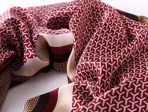 Macro shot of silk scarf fabric showing luxurious wine red geometric Goyardine patterns