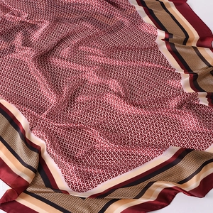 Macro detail of wine red silk scarf featuring elegant geometric patterns and striped borders