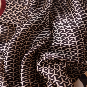 Close-up of silk scarf with geometric Y-pattern and elegant dark red rolled edges