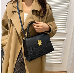 Detail of black faux crocodile leather crossbody bag with elegant gold metal buckle