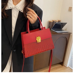 Detail of red croc-effect bag with gold clasp and smooth leather panel stitching