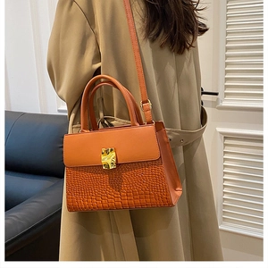 Detail of orange-brown croc-embossed handbag showing smooth leather mix and gold lock