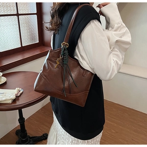Detailed view of a vintage brown leather tote bag worn as a shoulder bag in a retro setting
