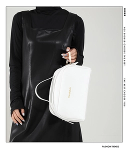 Detailed close-up of white lychee pattern leather pillow bag with gold lettering logo