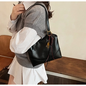 Chic black vintage underarm tote bag with elegant tassel and key charm detail