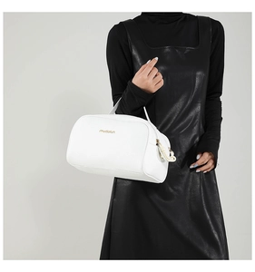 Detail of white textured leather handbag featuring a gold logo and braided rope zipper pull